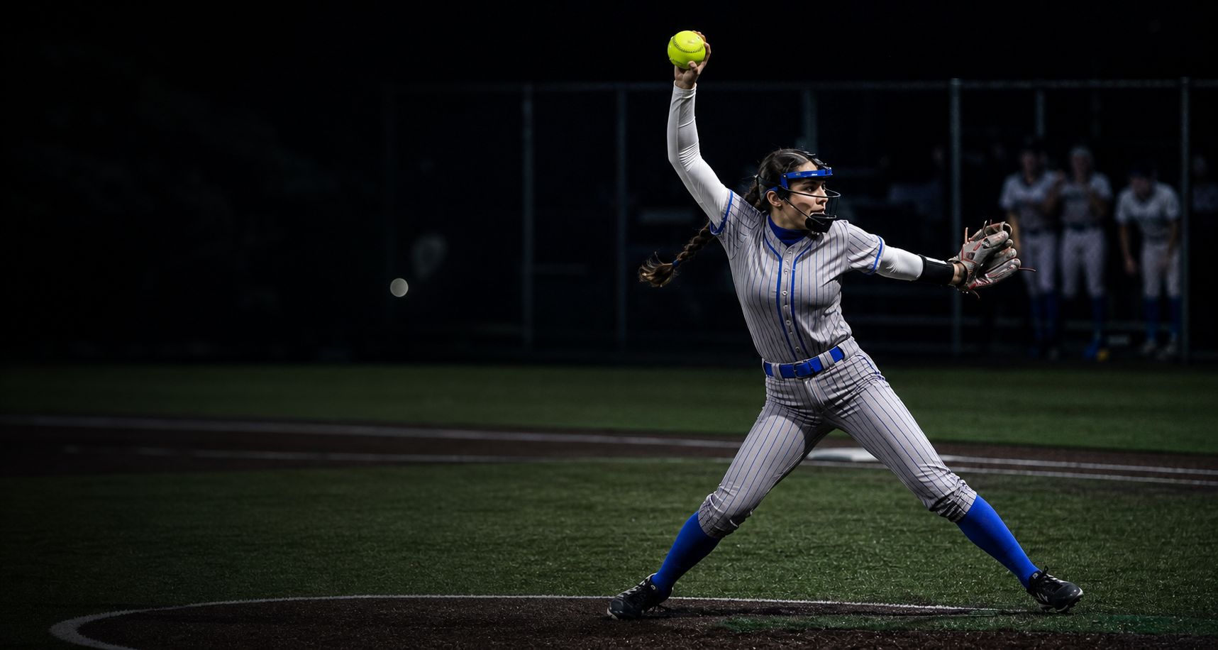Softball pitcher throwing under stadium lights